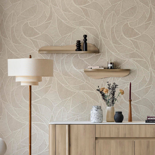 A styled interior scene showing a light wood sideboard or credenza against a beige patterned wallpaper wall, with a floor lamp, chair, rug, and staircase visible in a real room setting.