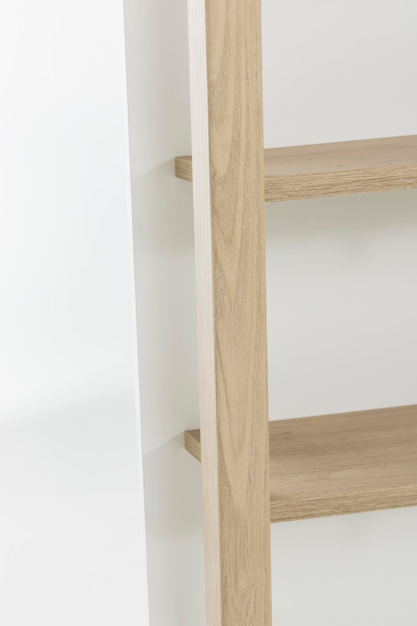 Wooden ladder shelf against a white wall