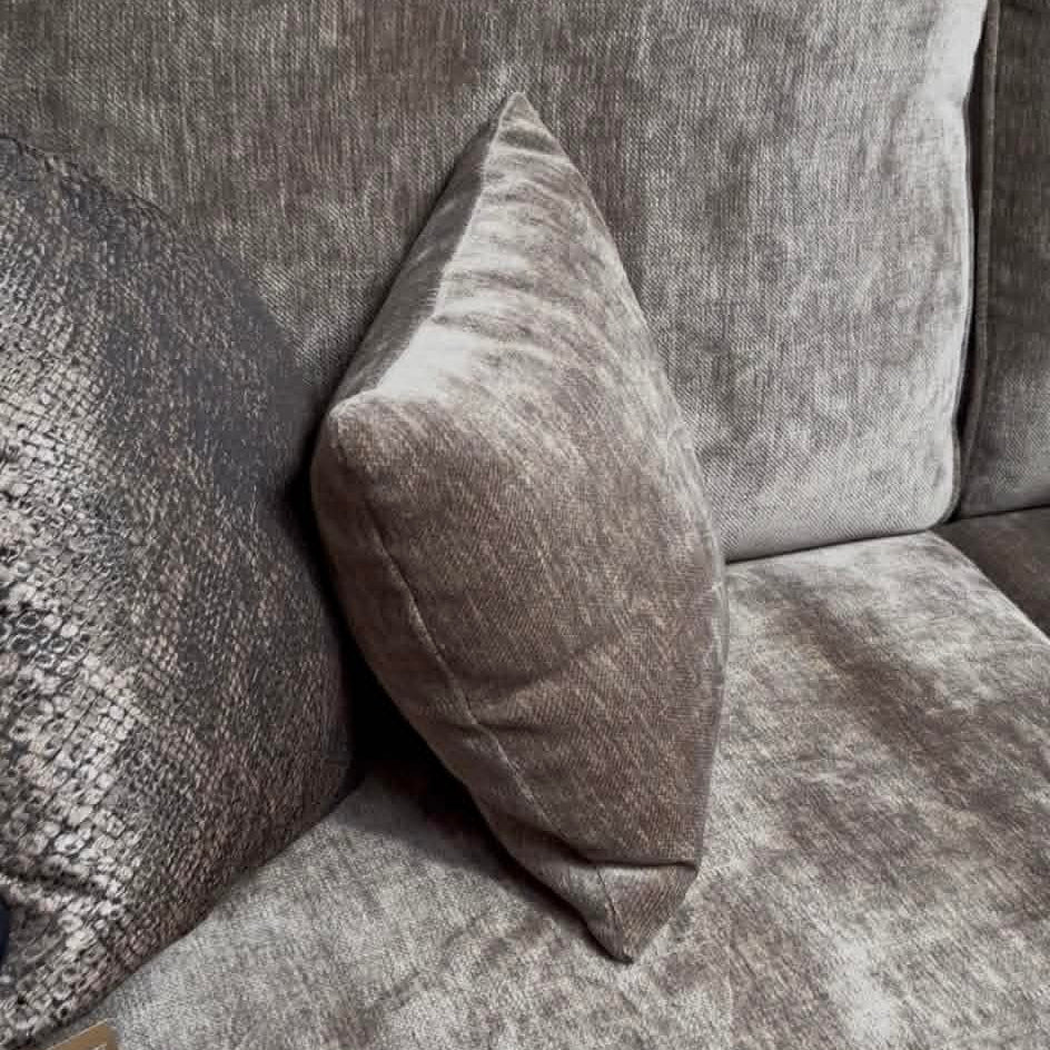 Gray textured sofa with a single pillow on a plain background